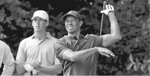  ?? CURTIS COMPTON/ AP ?? Defending champ Tiger Woods tees off on the 14th hole Thursday at Augusta National as Andy Ogletree looks on. The first round will finish Friday morning.