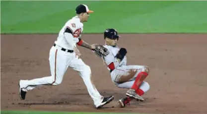  ?? —AFP ?? BALTIMORE: Manny Machado #13 of the Baltimore Orioles tags out Mookie Betts #50 of the Boston Red Sox between second and third base for the second out of the fifth inning at Oriole Park at Camden Yards on Monday in Baltimore, Maryland.