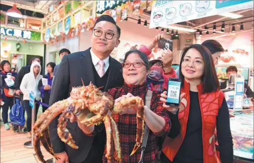  ?? XINHUA ?? A woman shows the Alaska king crab she purchased with just one HK dollar (13 US cents) during a street market promotion event hosted by Alipay in Hong Kong on Dec 12, 2017.