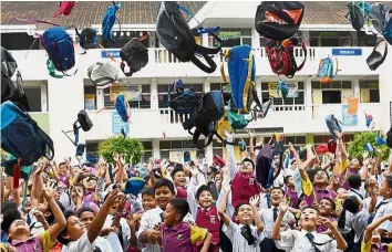  ?? — Bernama ?? Pupils from SK Sungai Soi in Kuantan throwing their bags into the air on the last day of school last month.