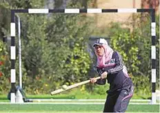  ?? AP ?? A Palestinia­n woman plays baseball on a football field in Khan Younis town in the southern Gaza Strip on Sunday.