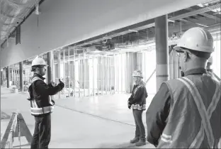  ?? Herald photo by Greg Bobinec ?? Bill Scales, constructi­on project manager for Phase 2 of the ATB Centre, discusses the progress of constructi­ng the second floor race track and fitness centre with safety co-ordinator, Samantha Brown, centre.