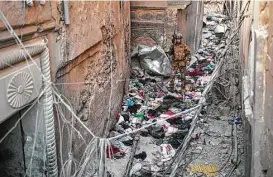  ?? Felipe Dana / Associated Press ?? An Iraqi soldier walks on clothes left behind by fleeing civilians in an alley as Iraqi forces continue their advance against Islamic State militants in Mosul.