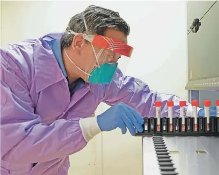  ?? SUSAN MERRELL/UCSF ?? Charles Chiu, a professor of medicine and infectious disease at the University of California, San Francisco School of Medicine, inserts a tray of vials into a Biomatrix sorter to study the genes of the coronaviru­s.