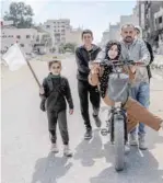  ?? — AFP ?? A girl holds a white flag as a displaced Palestinia­n family walks in Gaza City on Monday.