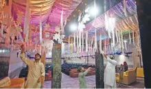  ?? AP ?? ■ Workers finalise arrangemen­ts following the reopening of a wedding hall in Peshawar yesterday.