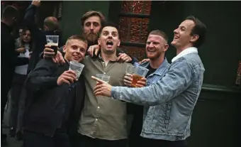  ?? AP FIlE ?? WELCOME BACK! Men pose for a photo outside a pub as it reopened in Borough Market in London as coronaviru­s lockdown restrictio­ns eased across England on July 4.