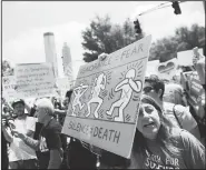  ?? AP/DAVID GOLDMAN ?? Jennifer Thompson (right) protests Friday across the street from National Rifle Associatio­n’s annual convention in Atlanta.