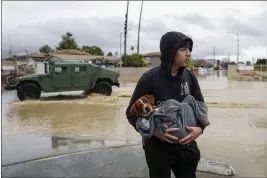  ?? SHAE HAMMOND — BAY AREA NEWS GROUP VIA AP, FILE ?? Esteban Sepulveda holds his dog Milo while leaving his home in Pajaro Valley on Sunday. Record snowfall and rain have helped to loosen drought's grip on parts of the western
U.S. as national forecaster­s and climate experts warned Thursday that some areas should expect more flooding as the snow begins to melt.