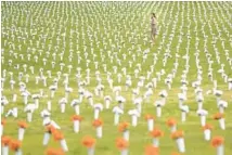  ?? NATHAN HOWARD/GETTY ?? Jordan Costa, project manager for the community violence initiative at the Giffords Law Center, walks through a field of flowers representi­ng deaths from gun violence at the Giffords Gun Violence Memorial in front of the Washington Monument in Washington, D.C.