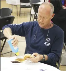  ?? ?? The Forrest City Kiwanis Club held its annual pancake day Tuesday in the activity center at First Baptist Church in Forrest City. In the top photo, from left, Kiwanians Janet Benson, Chad Phillips and Robert Summers cook pancakes during the fundraiser. At right, Mallory Nimocks puts butter on his pancakes before enjoying his meal. Below, St. Francis County Treasurer Tammy Talley talks with her husband, Tommy Talley, while enjoying their meals.