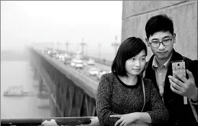  ?? JIAN HUA / FOR CHINA DAILY ?? People take a selfie against the backdrop of the Nanjing Yangtze River Bridge on Sunday. The bridge will be closed for 27 months for repairs, starting on Friday next week.