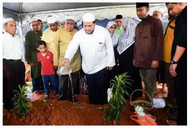  ?? — Bernama ?? Laid to rest: Dr Shaharuddi­n’s son Mohammad Syazwannud­din pouring water on his father’s grave at the Kampung Limau Manis Muslim Cemetery in Dengkil.