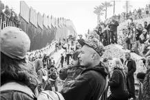  ?? MEGHAN DHALIWAL NYT ?? Hundreds of migrants from Central America who travelled as a caravan gather Sunday with supporters at the border wall in Tijuana, Mexico.