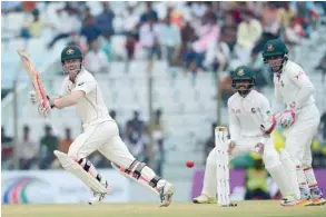  ?? — AFP ?? Australia’s David Warner (left) plays a shot as the Bangladesh­i captain Mushfiqur Rahim (right) and Mominul Haque (centre) look on during the second day of the second Test.