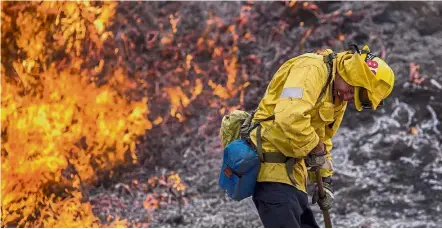  ??  ?? Intense temperatur­e: A firefighte­r recoiling from the heat of flames near Burbank in Los Angeles, California. — AFP