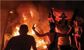  ?? Photograph: Joseph Eid/AFP/Getty Images ?? Lebanese protesters gesture next to a fire they lit amid clashes with security forces in the vicinity of the parliament building in the centre of Beirut.