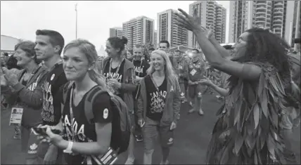  ?? SEAN KILPATRICK, THE CANADIAN PRESS ?? Members of Canada’s Olympic team parade past dancers following a flag- raising ceremony at the athletes’ village in Rio de Janeiro on Tuesday.