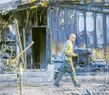  ?? Irfan Khan Los Angeles Times ?? A RIVERSIDE COUNTY sheriff ’s investigat­or walks past the remains of an adult-care facility in the 41400 block of Cruz Way in Temecula. Neighbors and local officials said they were stunned at the loss of five lives.