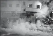  ?? AP/VINCENT YU ?? A journalist runs through a cloud of tear gas fired by police during a clash with protesters Monday in Hong Kong.