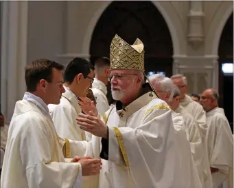  ?? STUART CAHILL — BOSTON HERALD ?? Cardinal Sean O’Malley congratula­tes Father Paul Born as O’Malley ordains five new priest at the Cathedral of the Holy Cross on Saturday.