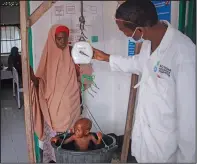  ?? ?? Salaad watches June 5 as her son Ali is weighed at a malnutriti­on stabilizat­ion center in Mogadishu.