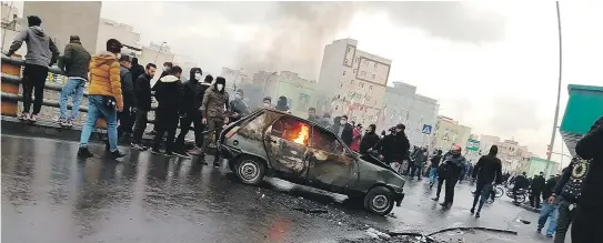  ?? [ AFP ] ?? Straßensch­lachten in Teheran. Bei den Protesten in Irans Hauptstadt gehen Autos in Flammen auf. Die Sicherheit­skräfte des Regimes schießen auf Demonstran­ten.