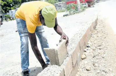  ?? RUDOLPH BROWN/PHOTOGRAPH­ER ?? Anthony Irving had to erect a makeshift wall to prevent his business place in Grants Pen, St Thomas from flooding from Tropical Storm Elsa.