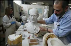  ??  ?? A worker places a copy of the head of Kouros in Culture Ministry’s Lab in Athens. Plaster replicas of Cycladic figurines are placed on a shelf storage in Culture Ministry’s Lab in Athens.