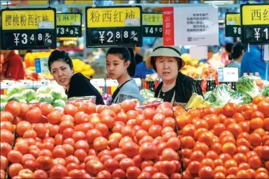  ?? WU JUNJIE / CHINA NEWS SERVICE ?? Shoppers choose vegetables at a supermarke­t in Taiyuan, capital of Shanxi province.