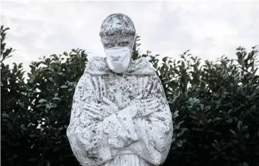  ?? | REUTERS ?? A PROTECTIVE mask had been put on the face of a statue of Italy’s patron saint, St. Francis, in San Fiorano, one of the towns on lockdown due to a coronaviru­s outbreak.