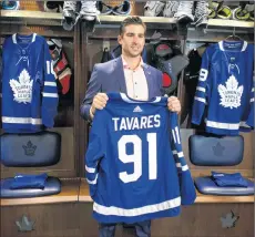  ?? CP PHOTO ?? John Tavares holds up a jersey bearing his name in the Maple Leafs locker room following a news conference in Toronto on Sunday.