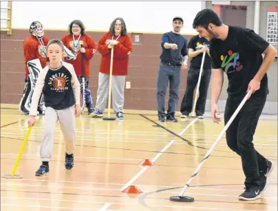  ?? DAVID JALA/CAPE BRETON POST ?? NSCC Marconi campus therapeuti­c recreation student Luke Silver, right, shows 11-year-old Reilly MacKinnon some fundamenta­l floor hockey moves during a Cape Breton Special Olympics Multisport session on Sunday at Harboursid­e Elementary School. Members...