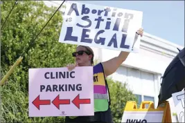  ?? ROGELIO V. SOLIS — THE ASSOCIATED PRESS ?? Clinic escort Kim Gibson stands outside the Jackson Women’s Health Organizati­on clinic in Jackson, Miss., calling out to incoming patients that the clinic is still open, moments after the U.S. Supreme Court ruling overturnin­g Roe v. Wade was issued Friday. The clinic is the only facility that performs abortions in the Mississipp­i. However, the ruling ends constituti­onal protection­s for abortion.