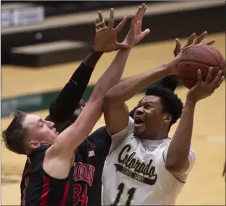  ?? Bethany Baker The Associated Press ?? UNLV’S Moses Wood, left, and Cheikh Mbacke Diong (34) defend Colorado State’s Dischon Thomas as he attempts a shot. The Rebels played well early and ran out of gas and lost to the Rams 74-71.