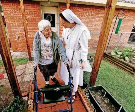  ?? [PHOTOS BY STEVE SISNEY, THE OKLAHOMAN] ?? Sister Maria Faulkner walks with Lucy Hooper in the backyard of the Gospel of Life Dwelling in south Oklahoma City.