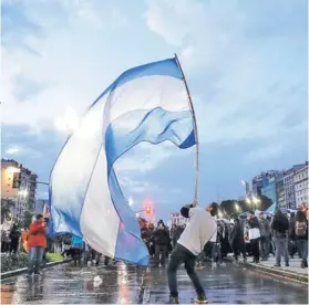  ??  ?? ► Un joven ondea una bandera argentina durante una marcha universita­ria, el jueves en Buenos Aires.