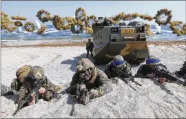  ?? KIM JUN-BUM / YONHAP 2016 ?? U.S. Marines (left) and South Korean soldiers — wearing blue headbands on their helmets — take positions after landing on a beach during a joint military amphibious exercise in Pohang, South Korea, in 2016.