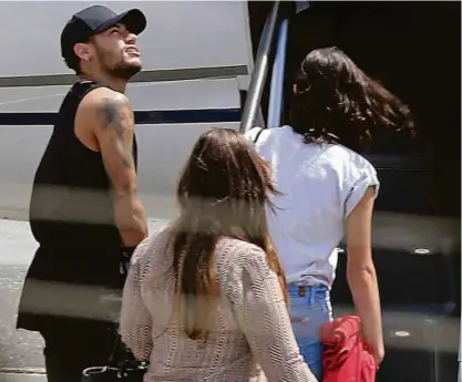  ?? Paulo Whitaker/Reuters ?? O atacante Neymar embarca ao lado da namorada, a atriz Bruna Marquezine, e a mãe dele, Nadine; a bordo de seu jatinho particular, o jogador viajou para Mangaratib­a, município no litoral do Rio de Janeiro