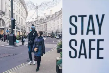  ?? ALBERTO PEZZALI/AP ?? Pedestrian­s keep their masks on outside Sunday as they make their way along Regent Street in London.