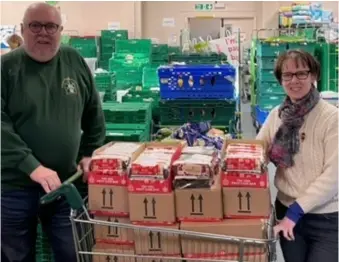 ?? ?? FESTIVE PRESENT: Jim Skinner from Pangbourne Rotary Club hands over a trolley load of Christmas cakes to Alison Peyton, ReadiFood’s manager