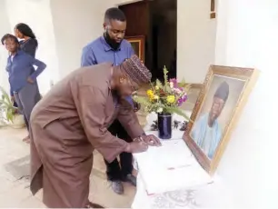  ??  ?? A sympathise­r signs the condolence register while the late Shagaya’s youngest son, John Nanzip Shagaya (Jnr) looks on