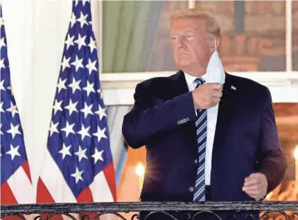  ?? WIN MCNAMEE/GETTY IMAGES ?? President Donald Trump removes his mask upon his return Monday to the White House from Walter Reed National Military Medical Center, where he spent three days being treated for COVID-19.