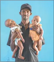  ??  ?? Abraha Gebremaria­m, 40, holds his 4-month-old twin daughters Aden (left) and Turfu, in the family’s shelter in Hamdayet. Abraha searches their faces for traces of their mother. Babies change, especially this young, he says. But for now, his family agrees, one of the girls does look like Letay.