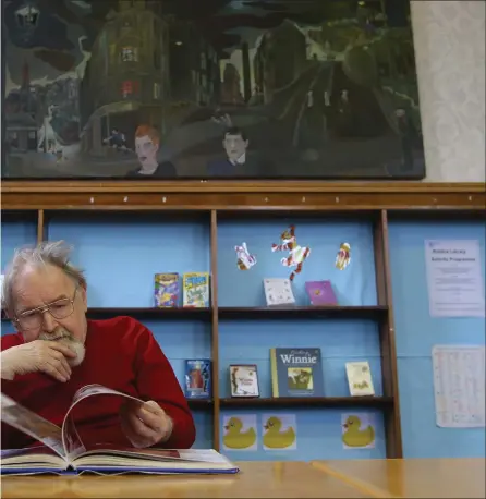  ?? PHOTOGRAPH: COLIN MEARNS ?? Alasdair Gray at Riddrie Library in Glasgow, where he spent much of his childhood. His 1964 painting Cowcaddens Streetscap­e in the Fifties hangs above