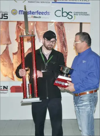  ??  ?? Joseph Stahl of Earview Colony receives the trophy and championsh­ip cup for the grand champion hog carcass from Doug Cramer.