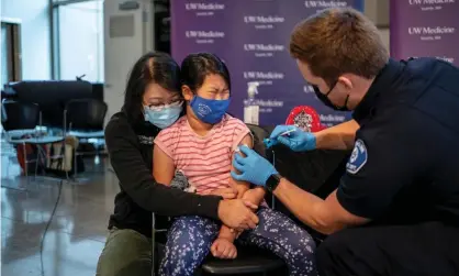  ?? Photograph: David Ryder/Getty Images ?? Elise Wong, 7, sits in the lap of her mother as she receives a Covid-19 vaccine in Shoreline, Washington.
