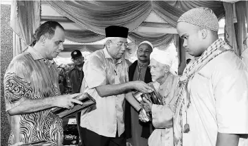  ??  ?? Mahdzir (second left) and Ghazali (left) handing out Aidil��tri contributi­ons to Se��olah Menengah Agama Amadiah Kuala Nerang founder Datu�� Ahmad Mohd Noor at the event in Kuala Nerang. — Bernama photo