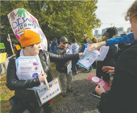  ?? ARLEN REDEKOP/PNG ?? Members of Autistics United, Breanna Himmelrigh­t, at left in the orange tuque, and Brayden Walterhous­e, centre in ball hat, hand out brochures during Autism Speaks Canada’s walk in Richmond on Sunday.