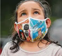  ??  ?? A girl wears a mask with Houston native Vanessa Guillén’s photo while attending a vigil on Sunday.